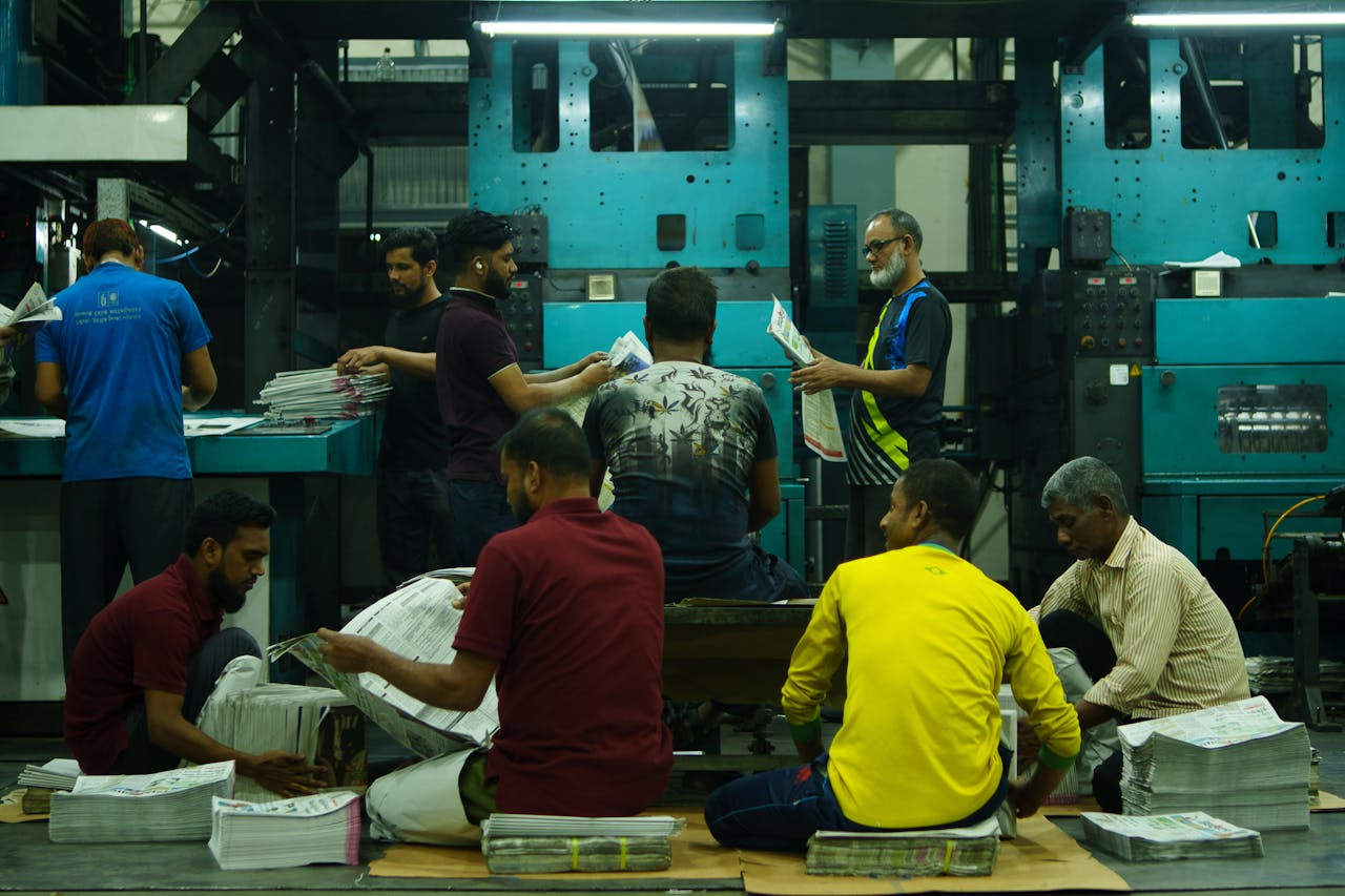 A team of workers sorting newspapers in an industrial printing factory.